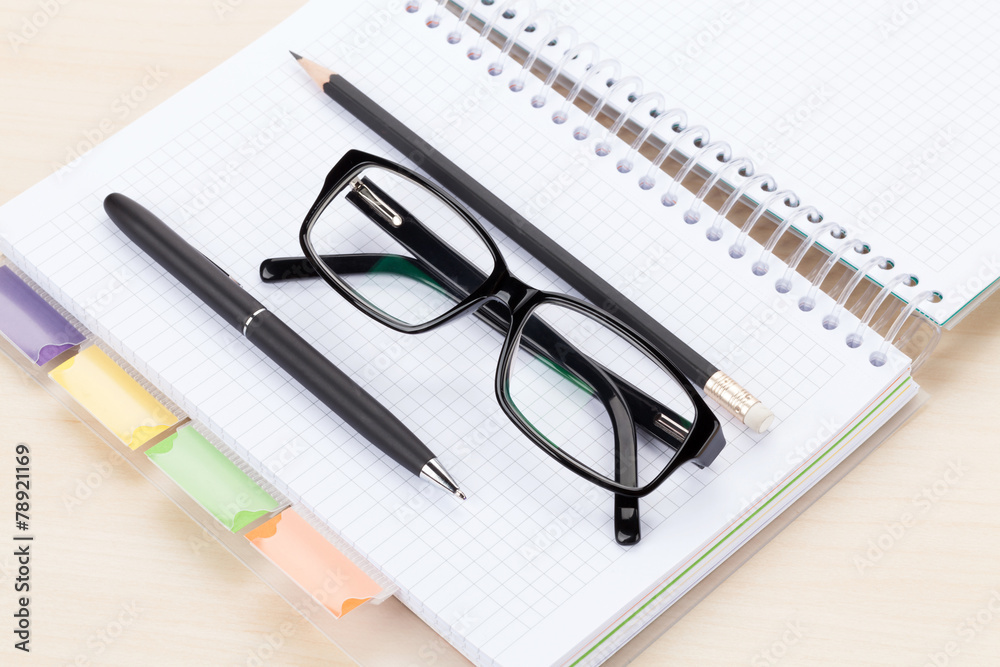 Office table with glasses over notepad, pen and pencil Office table with glasses over notepad, pen and pencil