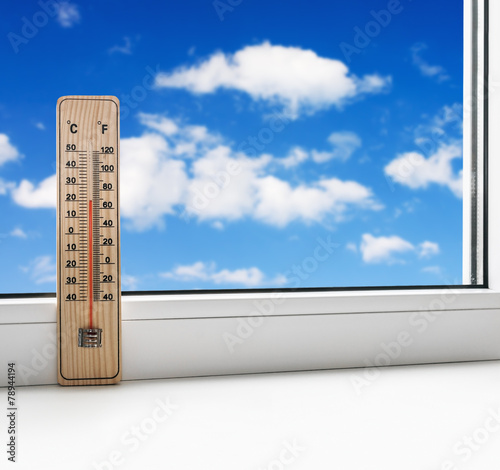 thermometer on the windowsill on a background of clouds