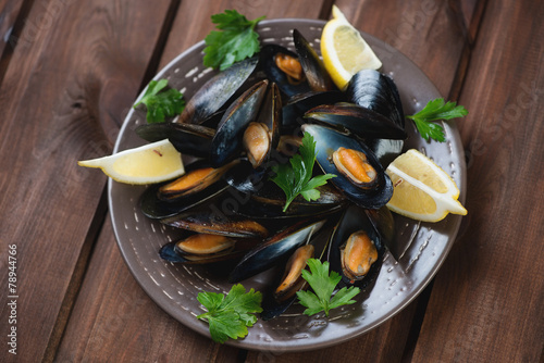 Steamed mussels with parsley and lemon, dark wooden background