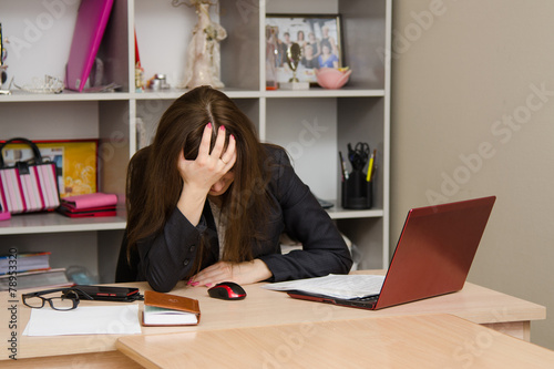 Girl in the office clutching her head photo