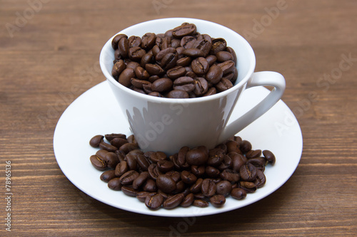 Cup with coffee beans on wooden table