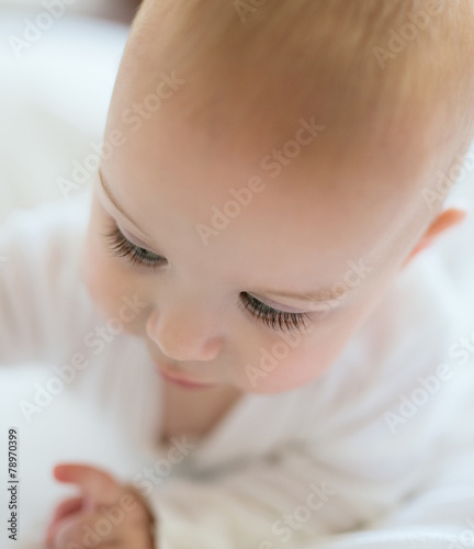 Portrait of a cute baby with gorgeous long eyelashes looking dow
