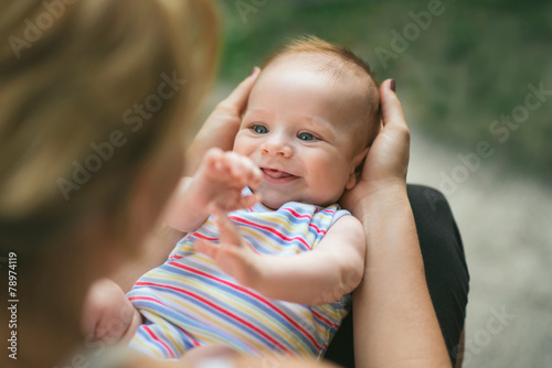 Adorable smiling baby held in his mother’s lap
