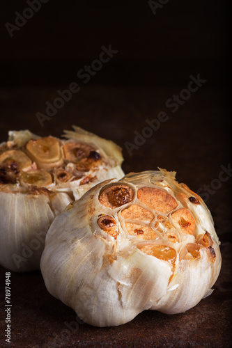 Roasted garlic heads on rustic surface