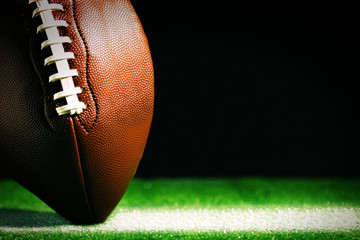 American football on green grass, on black background