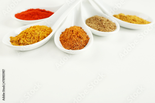 Different kinds of spices in ceramics spoons isolated on white