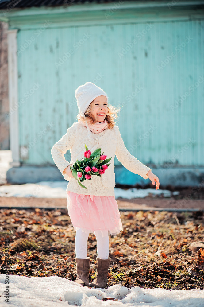 Fototapeta premium happy child girl on the walk in early spring with flowers