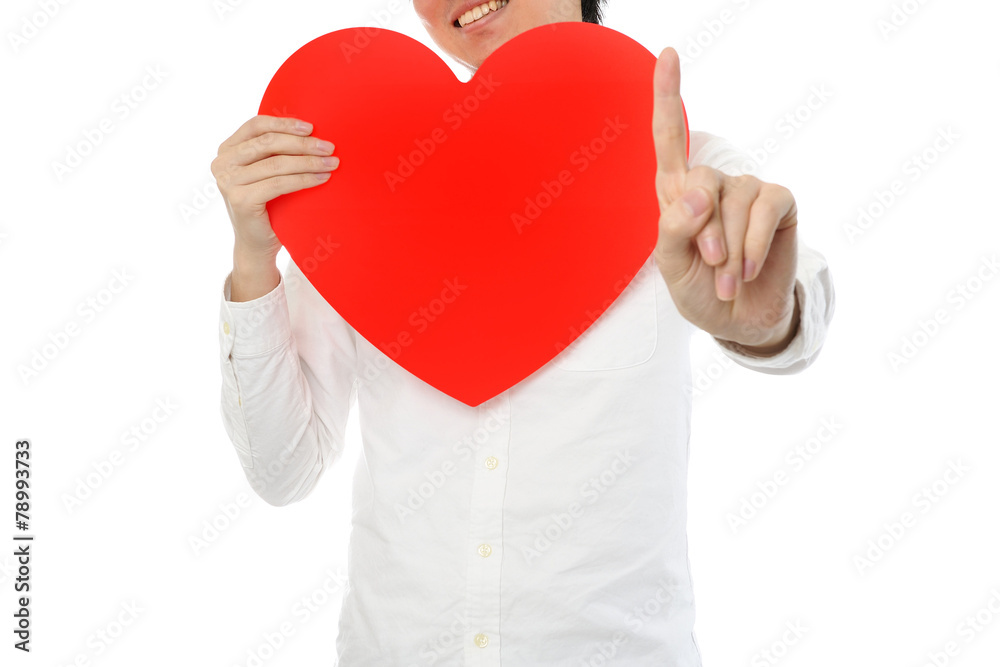 大きな赤いハートマークを持って指を指している男性