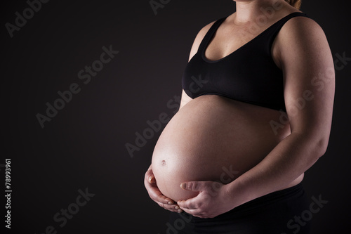 Pregnant woman holding his belly on black background