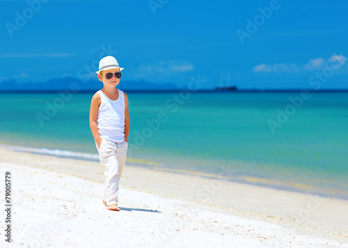 stylish kid boy walking the tropical beach
