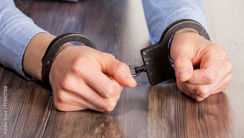 Foto Hands in handcuffs on the table