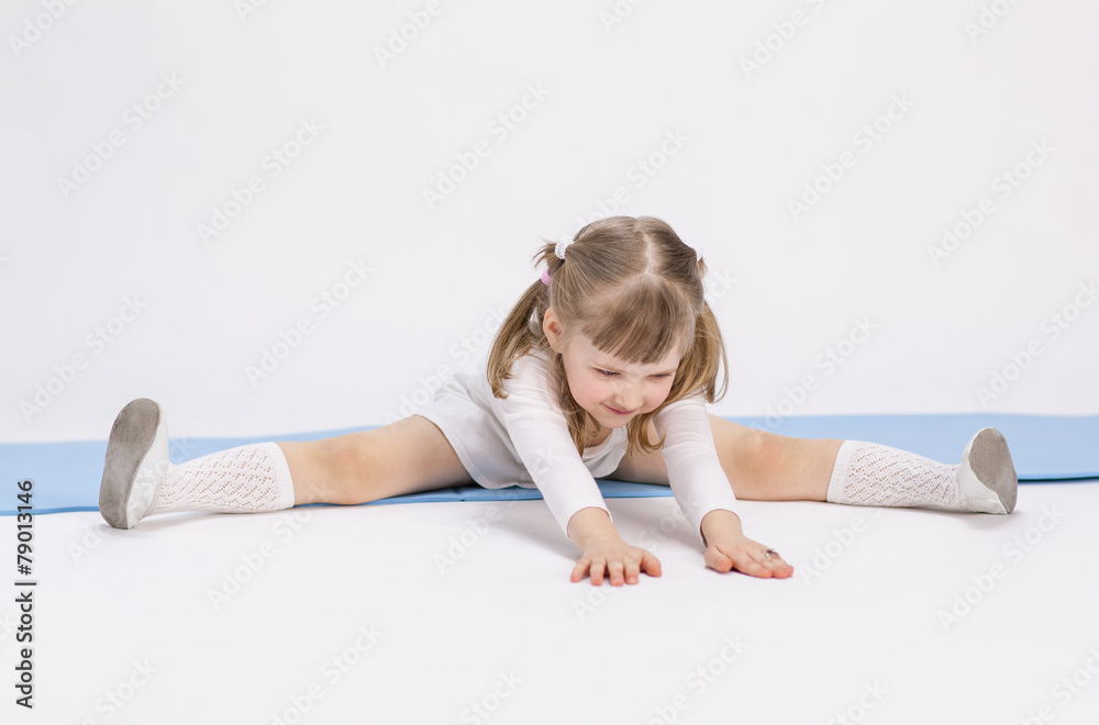 Pretty little girl sitting on the floor and doing exercise Pretty little girl sitting on the floor and doing exercise