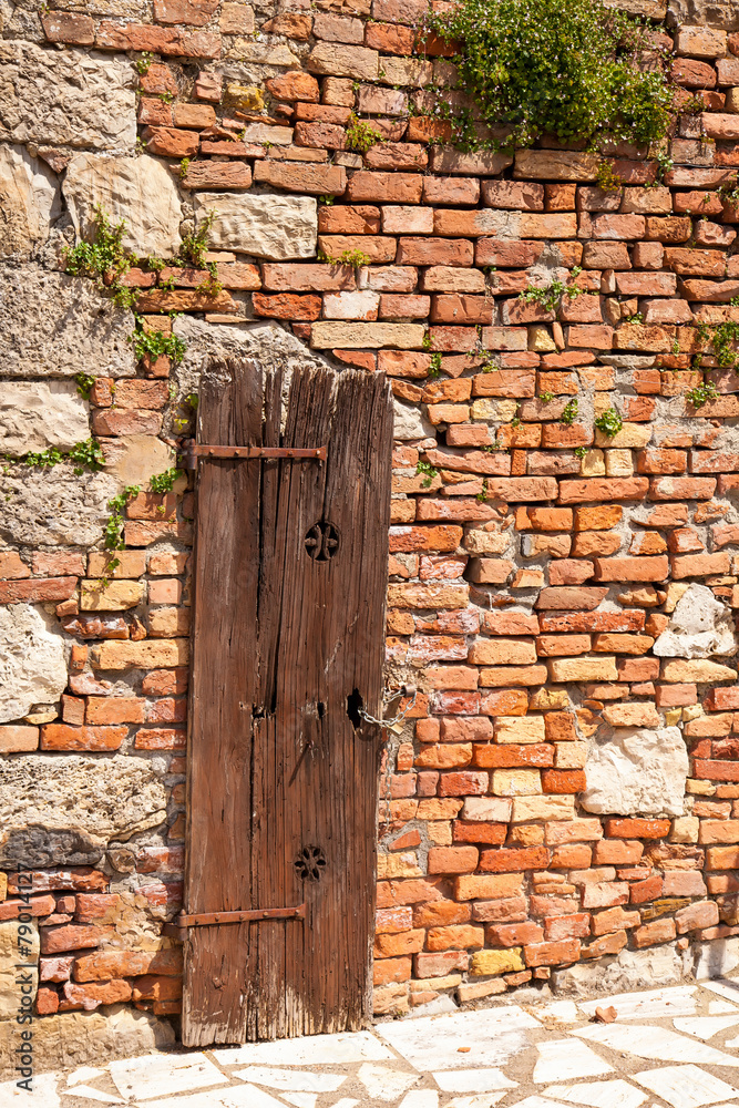 Brick wall of the old house with a wooden door Brick wall of the old house with a wooden door