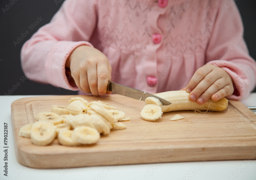 Little girl cutting a ripe banana Little girl cutting a ripe banana