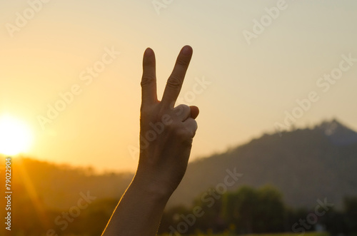 Hand showing peace victory sign against pure blue sky