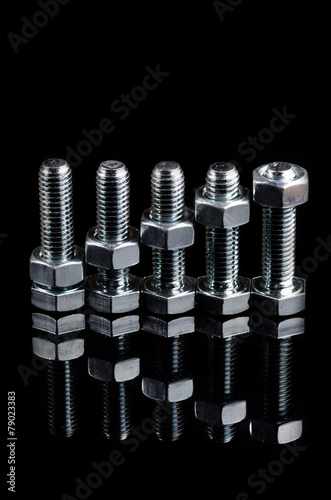 Bolts and nuts on the black background. Macro shot.