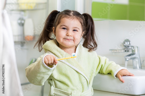 Smiling child brushing teeth
