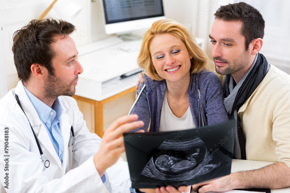 Fototapeta premium Doctor shows an ultrasound to a young happy couple