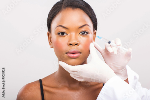 cosmetic surgeon injecting young african woman face
