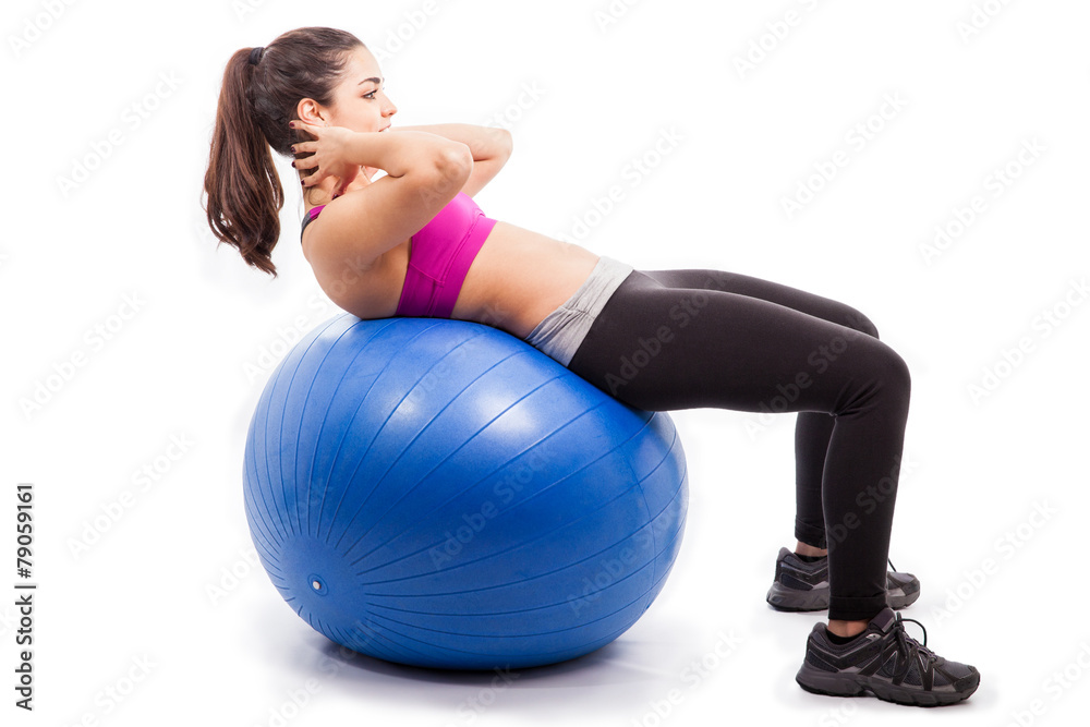 Fit woman doing crunches on stability ball in a studio