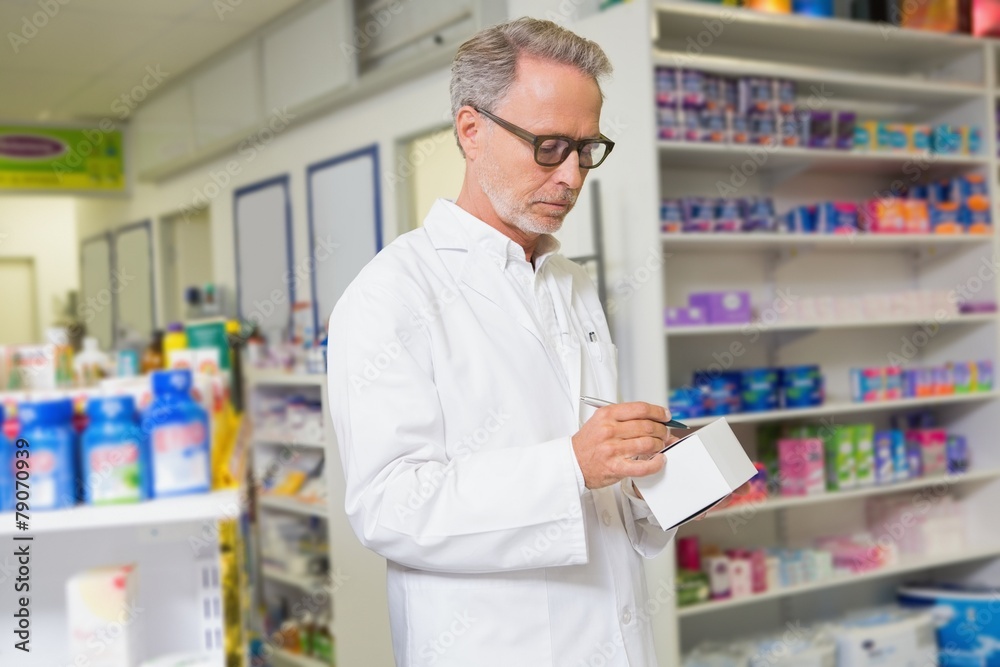 Focused pharmacist writing on box of medicine