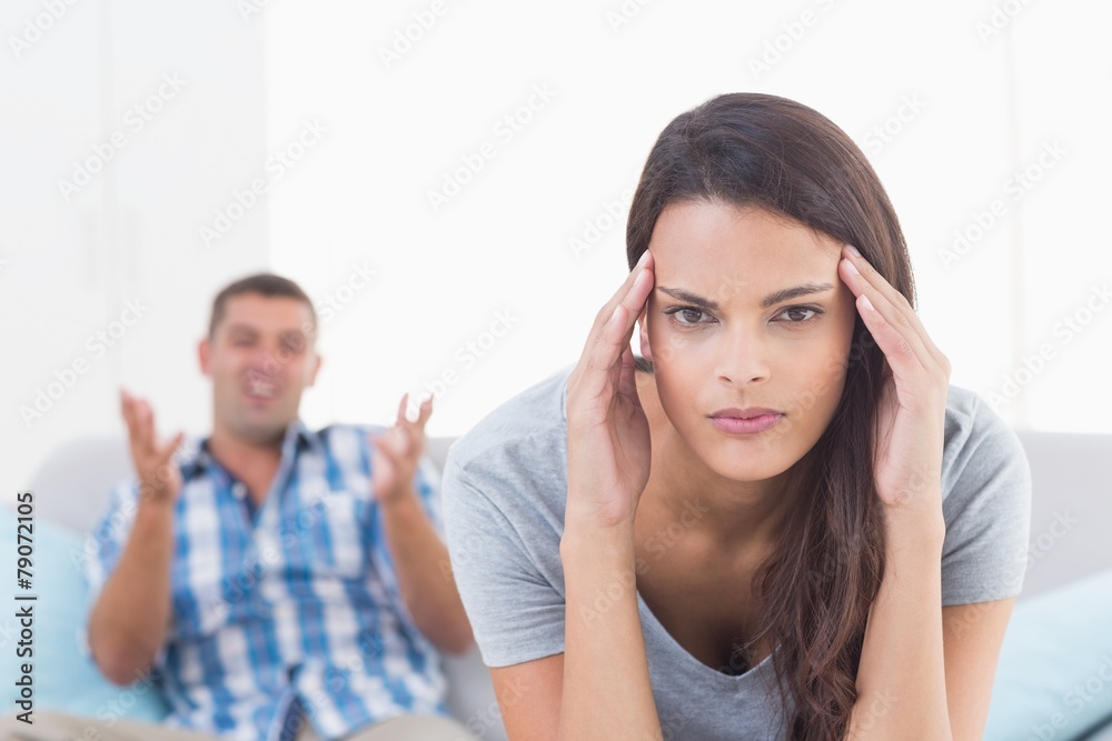 Woman suffering from headache while man arguing Woman suffering from headache while man arguing