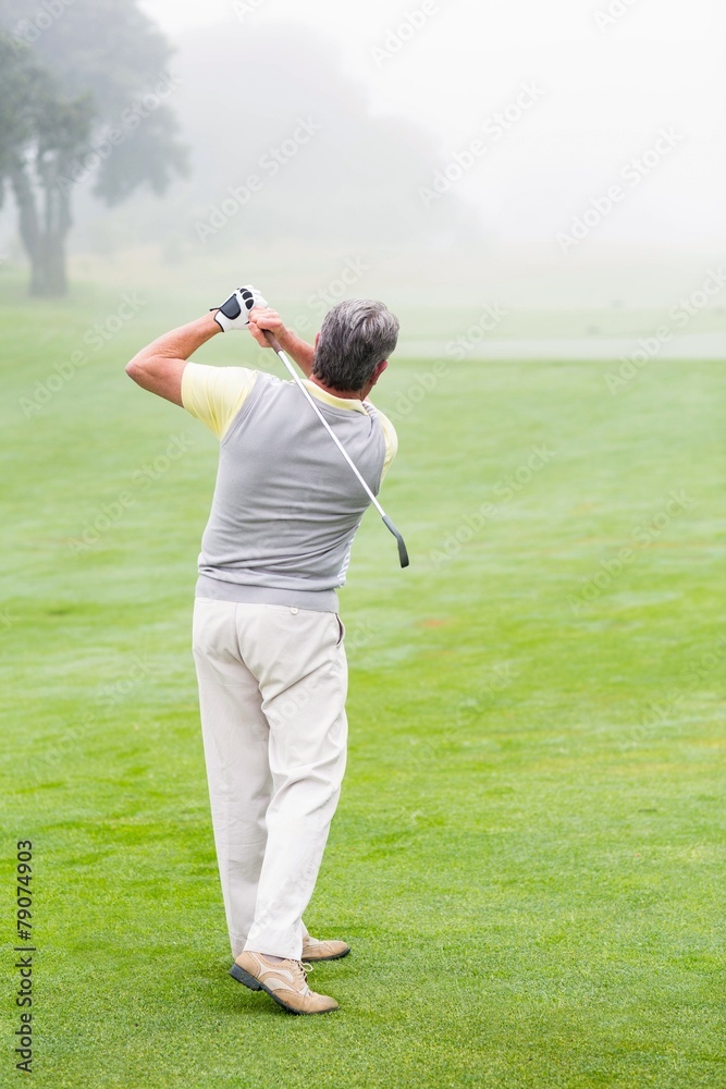 Golfer swinging his club on the course Golfer swinging his club on the course