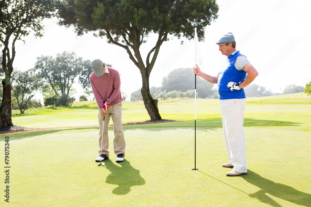 Obraz premium Golfer swinging his club with friend
