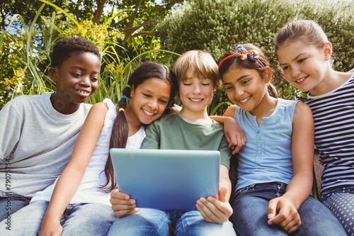Happy children using digital tablet at park