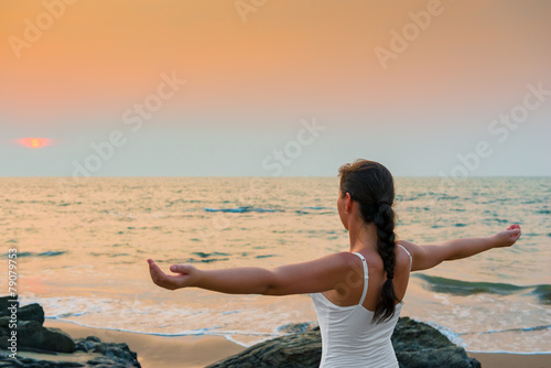 girl with his hands spread apart at sunset by the sea