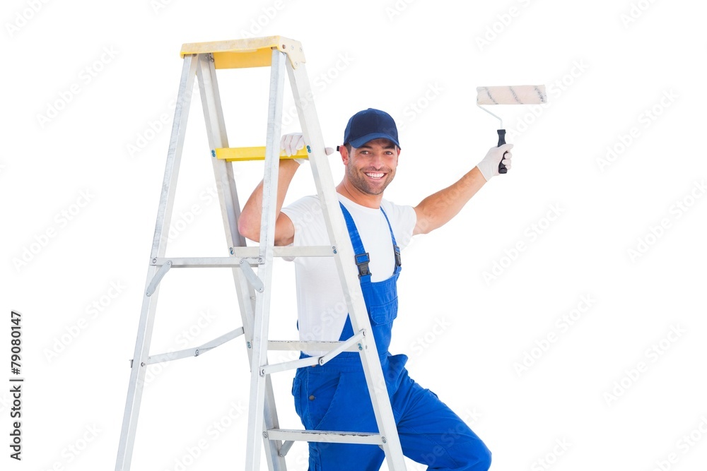Happy handyman on ladder while using paint roller Happy handyman on ladder while using paint roller