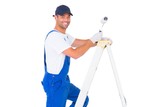 Happy handyman with paint roller climbing ladder