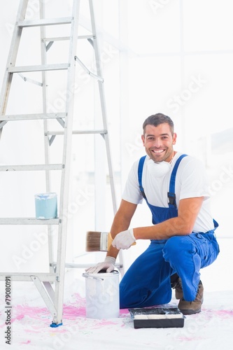 Smiling handyman with paintbrush and can at home