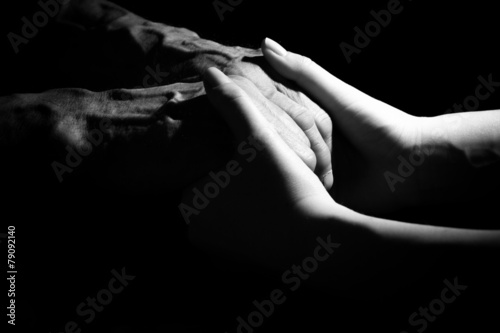 Hands of the old man and a young woman. in low key