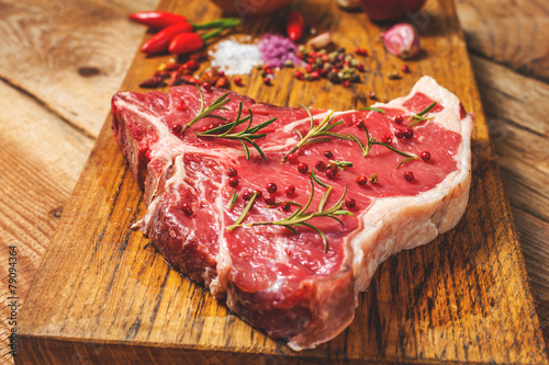 Close-up of fresh meat steak with spices on wooden background