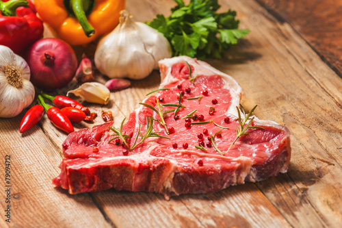 Close-up of fresh meat steak with spices on wooden background