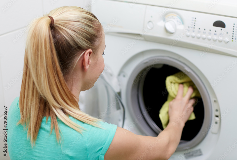 happy woman putting laundry into washer at home happy woman putting laundry into washer at home
