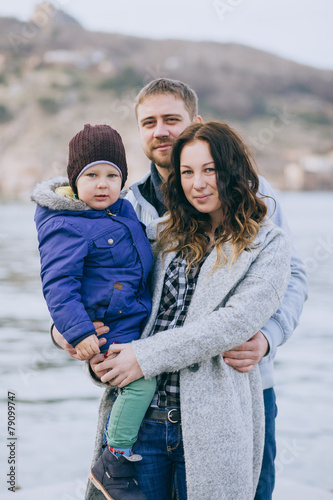 Happy family -mother, father and little son- walking in harbour