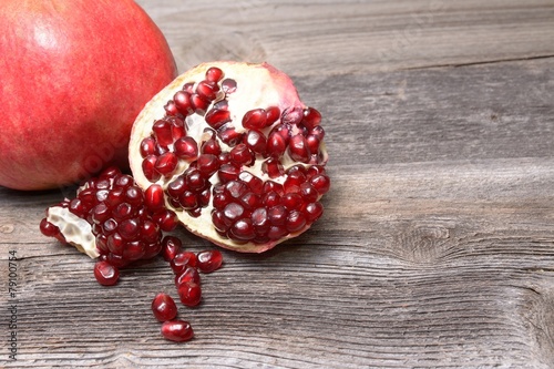 Red juicy pomegranate, on dark rustic wooden table photo