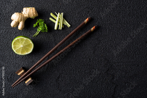 Chopsticks and food ingredients on black stone table top view