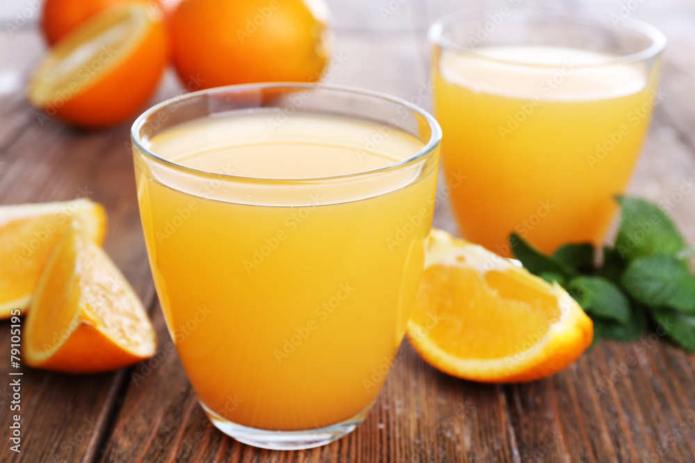 Glasses of orange juice with oranges on wooden table close up Glasses of orange juice with oranges on wooden table close up