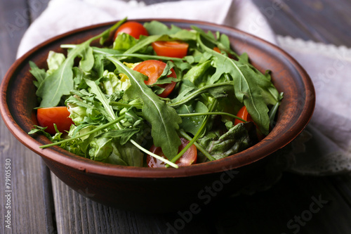 Salad with arugula and cherry tomatoes on wooden table