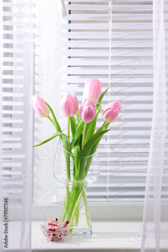 Beautiful pink tulips in glass vase on windowsill background