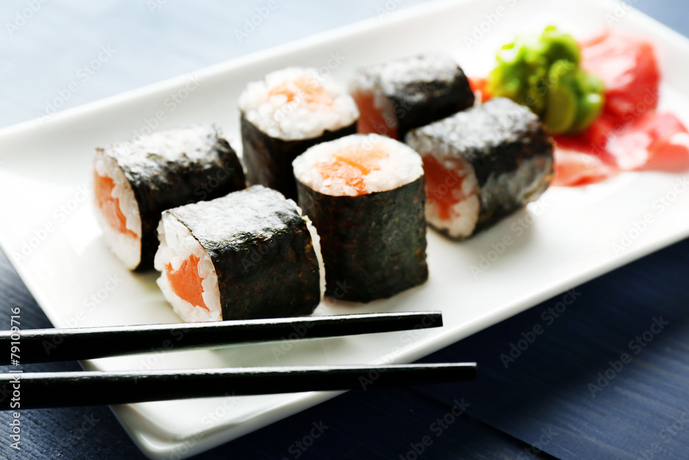 Sushi rolls with salmon on plate, on wooden background Sushi rolls with salmon on plate, on wooden background