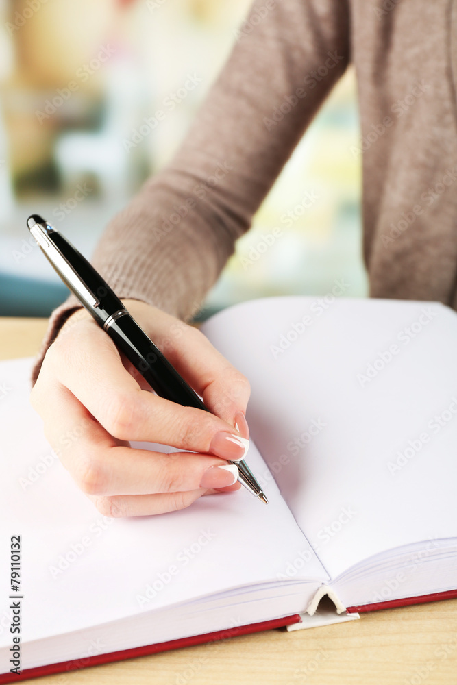 Female hand with pen writing on notebook, closeup Female hand with pen writing on notebook, closeup