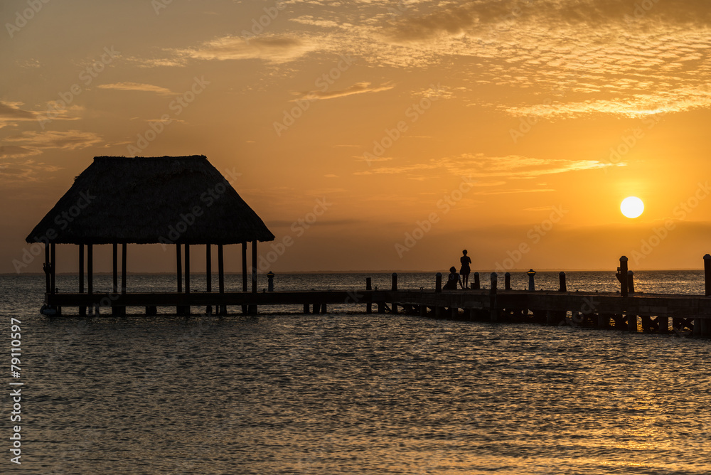 Couple in love at a wooden pier palapa enjoying Sunset at Holbox