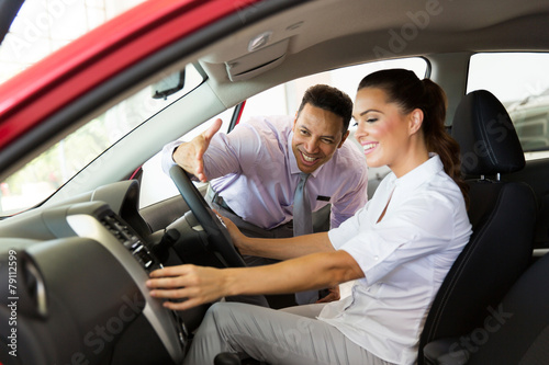 car sales consultant showing a new car to young woman © michaeljung