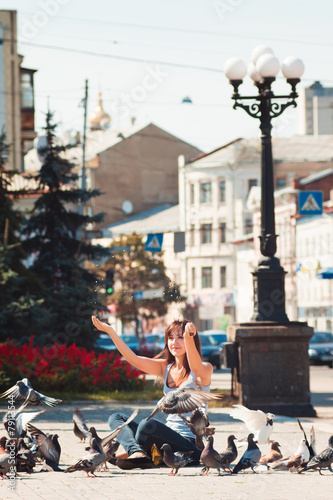 Feeding pigeons. Girl feeds pigeons in square in city © arvitalya