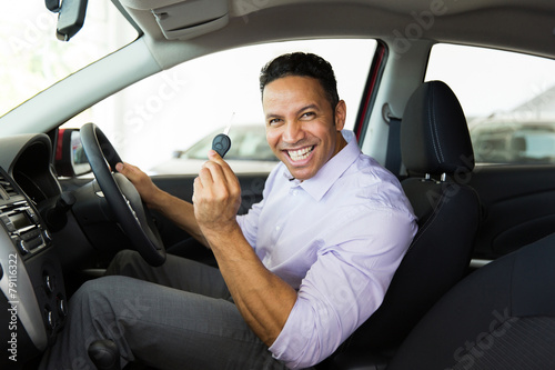 middle aged man showing a car key inside his new vehicle © michaeljung