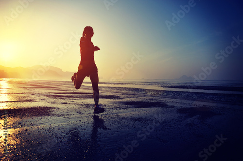 young woman running on sunrise beach  